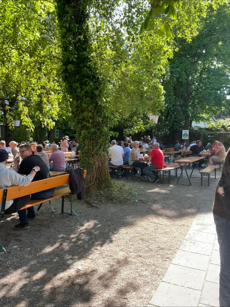 Gut besuchter Biergarten der Zur Aubinger Einkehr unter großen, schattigen Bäumen