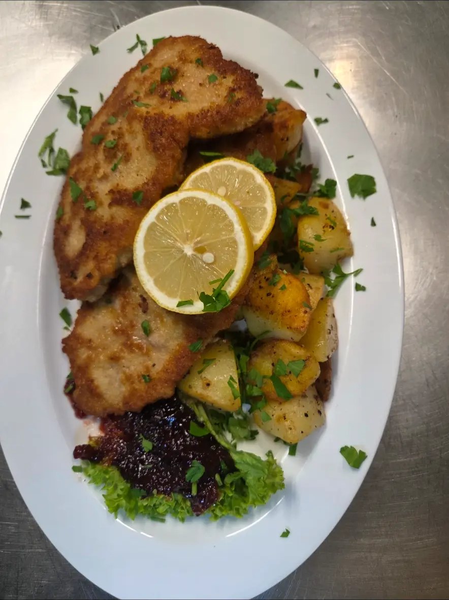 Paniertes Schnitzel mit Zitrone, Bratkartoffeln und Preiselbeeren