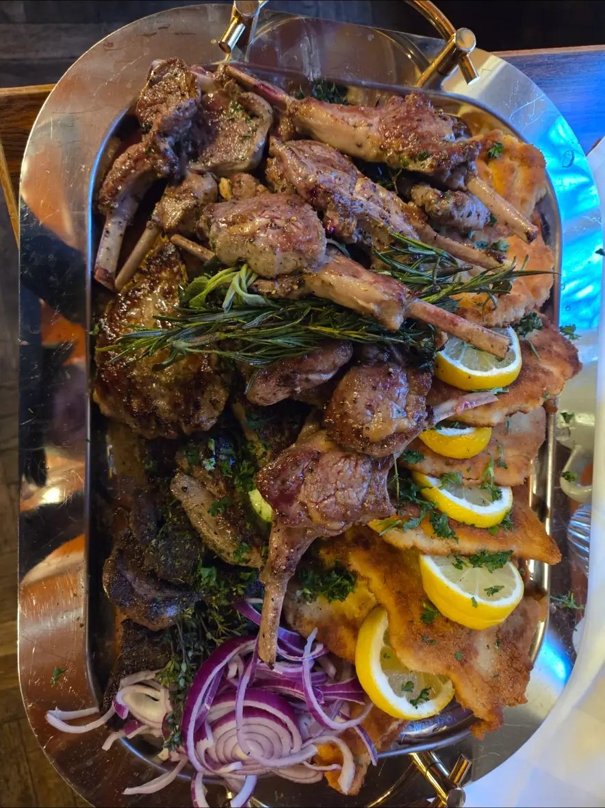 Große Grillplatte mit Lammkoteletts, Rosmarin, Zitrone und roten Zwiebeln