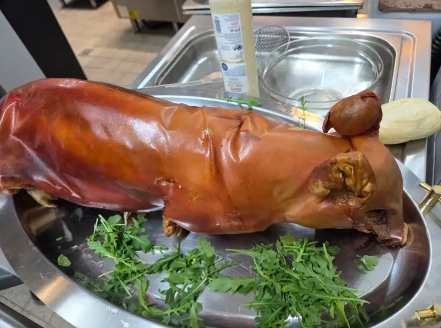 Knusprig gebratenes Spanferkel auf einer Platte mit Rucola