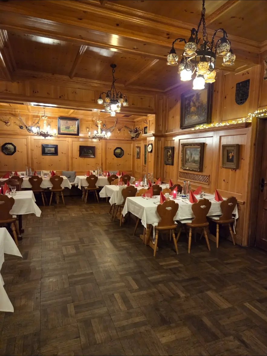 Holzvertäfelte Gaststube mit eingedeckten Tischen und Kronleuchtern